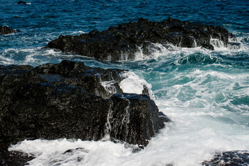 Vivid ocean waves splashing against rugged rocks on Jeju Island, capturing the raw power and beauty of nature
