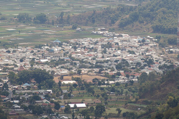 Aerial view of dense Indonesian village houses surrounding the central mosque and lush agricultural fields