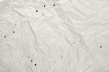 Crumpled light gray paper creating textured background with scattered glitter. Color of the Year concept
