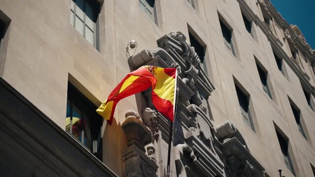 The Spanish flag waves on a stone building facade in central Madrid Spain