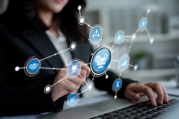 A professional woman engages with her laptop in a modern office setting. Digital business icons and graphics represent networking and data analysis for success. Crux