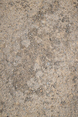 A close-up of compacted dirt mixed with small gravel and stones, showing natural earthy tones and rugged texture.