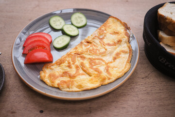 Freshly made omelet served with cucumber and tomato slices