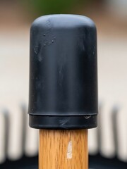 Protective black plastic cap atop of a wooden chair leg, close-up