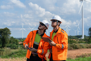 Renewable energy engineers review wind farm project plans and data to analyze the efficiency and safety of wind power generation systems.