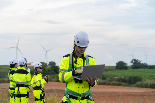 Renewable energy engineers review wind farm project plans and data to analyze the efficiency and safety of wind power generation systems.