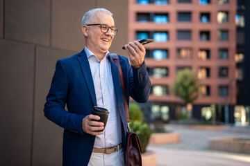 Mature businessman communicating using smartphone voice command
