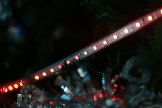 Red glowing bright led light strip decoration with festive illumination. Macro detail of diode lamp creating warm, magical atmosphere against dark, blurry background