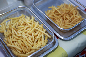 Satisfying close up of fresh golden french fry in two metal baskets. hot, crispy potato snack and popular food side dish prepared in restaurant kitchen for lunch