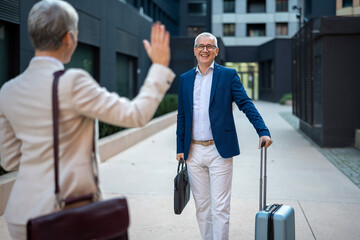 Businessman arriving at office building, greeting colleague