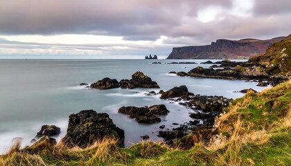 Obraz premium Coastal landscape features calm sea, rocky shore, cliffs under cloudy skies