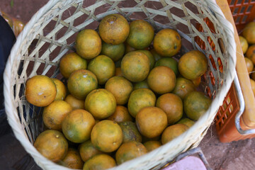 Woven basket full of fresh, organic orange fruit at local market. pile of healthy citrus showing natural abundance, healthy diet, and ripe for eating, food background