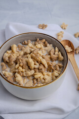 Bowl of maple leaf cereal with milk and wooden spoons on a white napkin