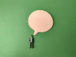 The miniature figure of a person stands beside a blank speech or thought bubble