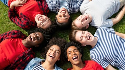 A circle of diverse young people laughing joyfully while lying on grass.