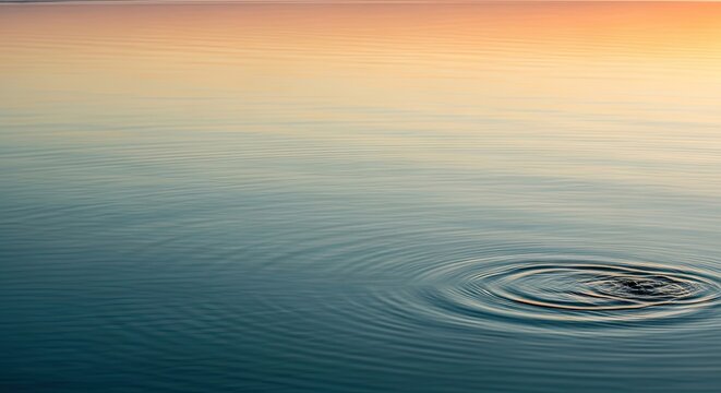 A serene lake at sunset with gentle ripples on the water's surface.