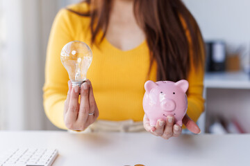 
Business, Financial and money planning idea, Clever thinking about money saving for future, woman calculating number of money, increasing coin stacked and holding light bulb on the table.