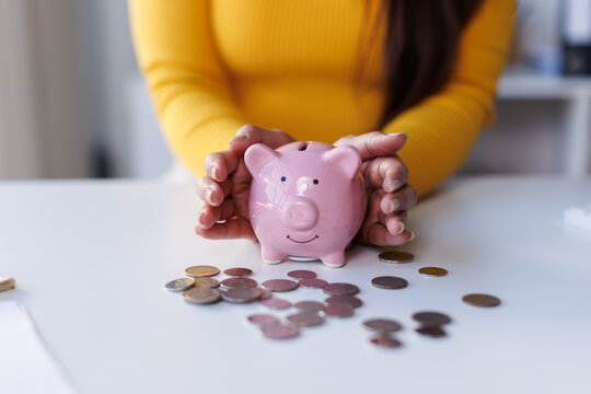 Saving money wealth concept, asian business woman hand putting coin into piggy for saving cost, cash finance planning to spend enough money on her income for save money, payment tax, investing.
