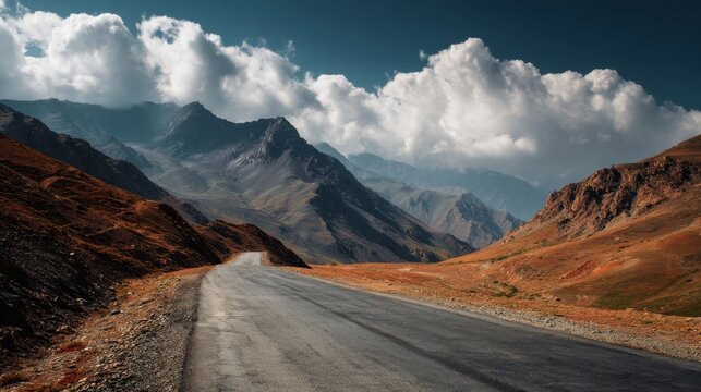 A scenic road curves through a dramatic mountain landscape. The sunlight casts a warm glow while fluffy clouds provide a stunning backdrop capturing the essence of wilderness. - Powered by Adobe