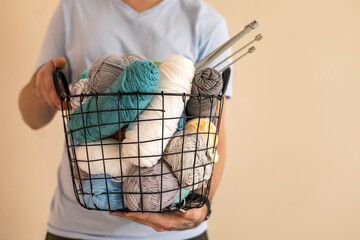 A man holds a large basket with colorful yarn.