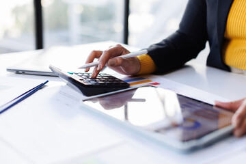 Business woman working on laptop, using tablet at modern office, analyzing business document with financial graph, market report on digital tablet, business data analysis concept
