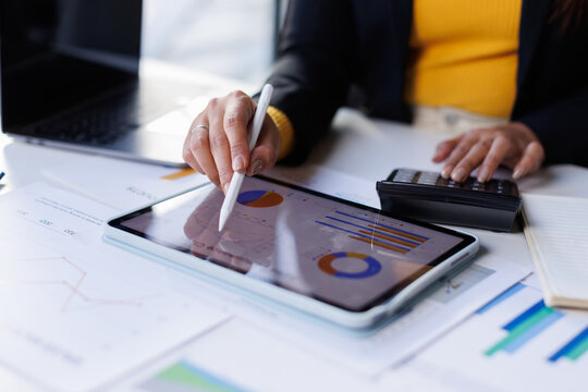 Business woman working on laptop, using tablet at modern office, analyzing business document with financial graph, market report on digital tablet, business data analysis concept

