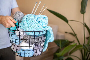 A man holds a large basket with colorful yarn.