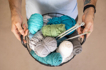 A man holds a large basket with colorful yarn.