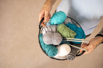 A man holds a large basket with colorful yarn.