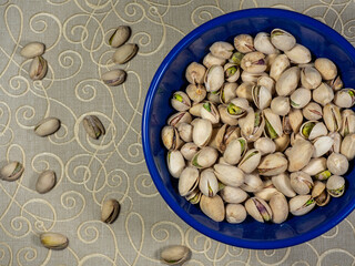 Salted and roasted pistachios in a blue bowl. Pistachios help harmonize the body's water balance, strengthen bones and teeth, release and produce energy, improve metabolism and absorption 