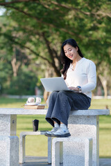 Obraz premium Asian woman studying online using laptop outdoors