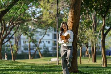 Young woman enjoying reading book in green park