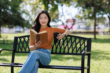 Obraz premium Young asian woman reading book in park
