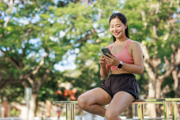Smiling woman checking smartphone during outdoor workout break