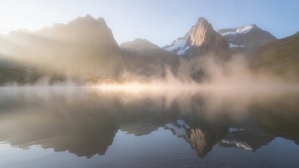 Misty mountain lake at sunrise with sun rays and reflections