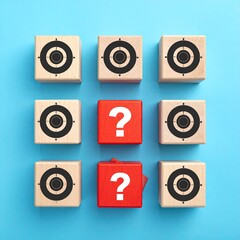 Nine wooden blocks arranged in a grid pattern.  Six blocks feature target icons, while two red blocks display a question mark.  The blocks sit on a light-blue surface