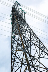 Tall metal electricity transmission tower against cloudy sky