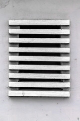 White ventilation grate on gray wall with horizontal slats