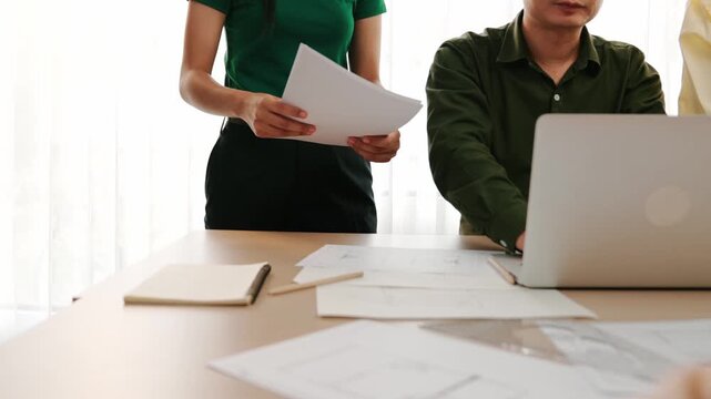 Architect and engineer compare construction detail blueprint display in laptop on table with architectural document or plan and measurement tool for accuracy at modern office. Closeup. Delineation.