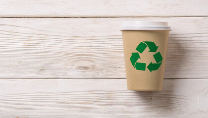 Brown Paper Coffee Cup with Green Recycling Symbol on White Wooden Background for Sustainable Lifestyle