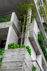Modern concrete building with green balconies and lush foliage enhancing urban architecture