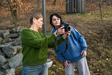 Two Russian women in their 50 years old and 60 years old enjoy photography outdoors, showing active aging, mindfulness, friendship and the joy of pursuing a creative hobby.