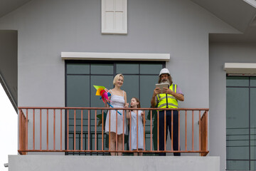 Experienced bearded foreman shows new home plans on a tablet to a smiling mother and daughter, highlighting family trust, smart construction technology and a warm, hopeful future in their house