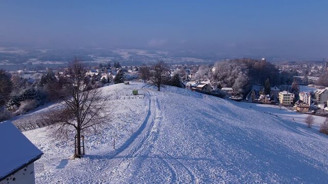 Aerial over top of a snowy hill with a walking path, Uster, Switzerland