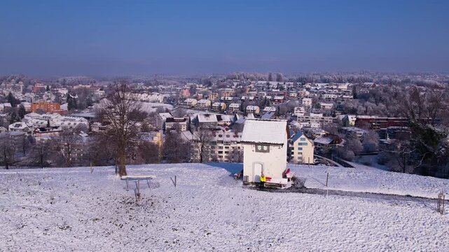 Top of a snowy hill with a tiny house with city in background, Uster, Switzerland