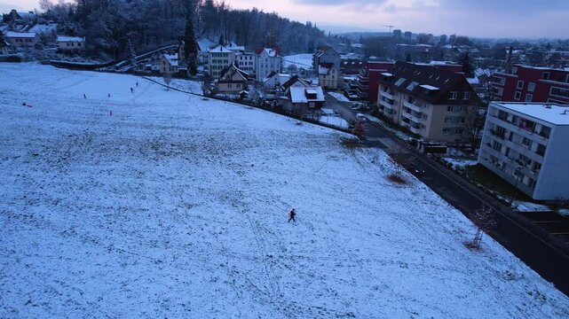 Aerial of a man walking home with his wood sledge in hand, Uster, Switzerland