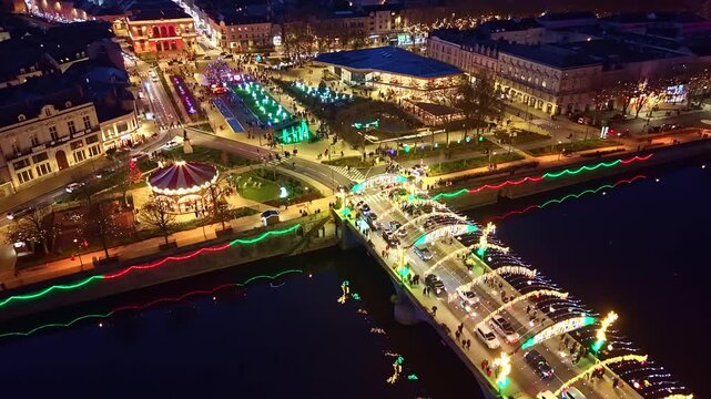 Closer drone fly toward the November 11th Square and illuminated Aristide-Briand Bridge during Christmas market, Laval, Mayenne, France