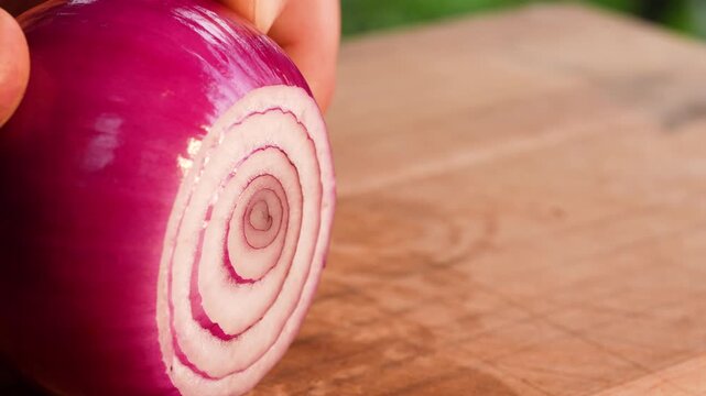 Slow-motion close-up of a red onion as a thin slice is smoothly removed with a sharp knife. The crisp layers, gentle blade movement and clear texture create a precise and detailed cutting moment.