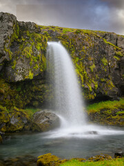 Obraz premium Clear water cascading over a small mossy waterfall in Western Iceland Kirkjufell mountain