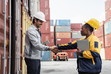 Man hand shake with woman logistics workers in high visibility safety gear discuss operations and checking container at shipping container yard	
